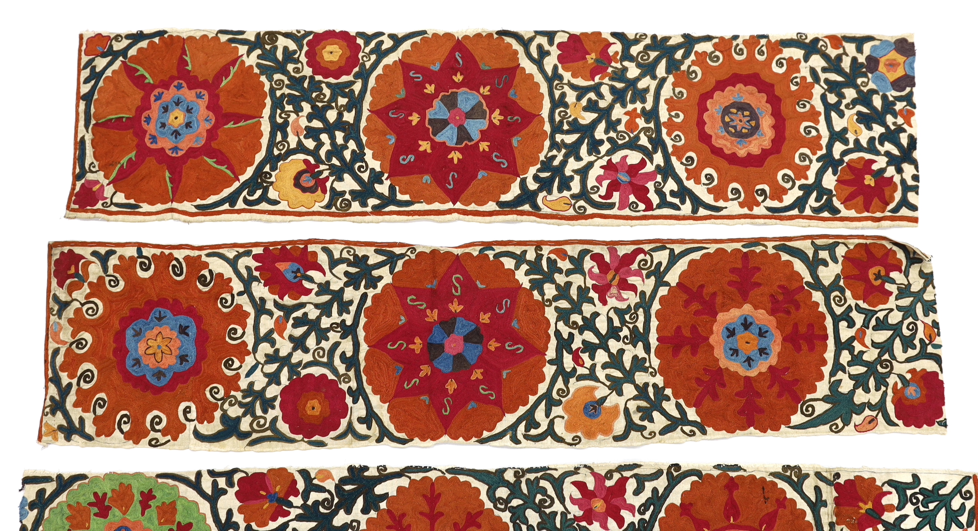 Four early 20th century Uzbek Suzani panels, embroidered with hand dyed silk on thick woven linen, in large brightly multi-coloured symbolic motifs, possibly embroidered for a larger prayer rug or hanging, longest 125cm